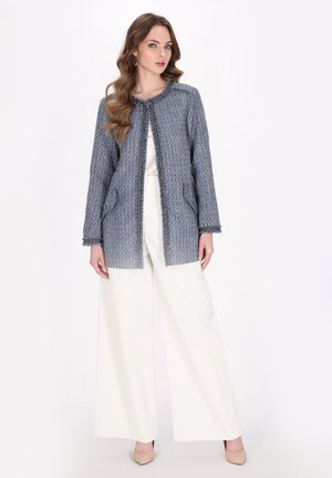 Jachetă din tweed texturat albastru, cu guler rotund și deschidere frontală. Are buzunare frontale și este asociată cu pantaloni albi cu picioare largi.