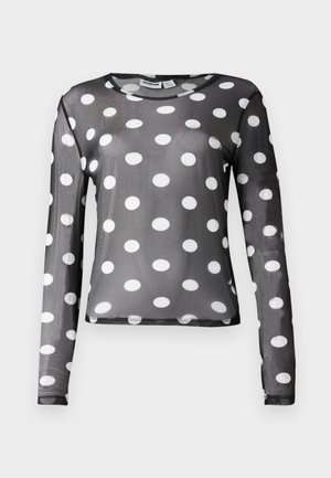 Chemise en maille noire à manches longues avec de grands pois blancs. Pourvue d'un col rond et d'une texture lisse, avec une silhouette ajustée.