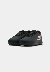 Black low-top sports shoes with black laces and textured soles, featuring a small white and orange logo on the side.