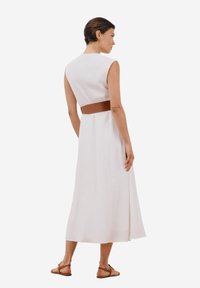 Abito bianco senza maniche con corsetto aderente e gonna fluida, dotato di una cintura marrone in vita. Tessuto liscio con una silhouette pulita.