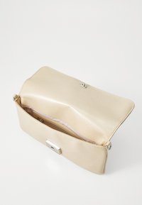 Pochette en cuir beige ouverte montrant une poche zippée intérieure et un fermoir en argent sur fond blanc.