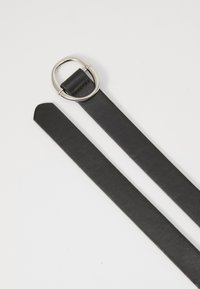Cinto de couro preto com uma fivela circular prateada. O cinto tem uma textura suave e um design plano, apresentando uma extremidade pontiaguda.