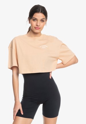 Cropped peach t-shirt with a round neckline and short sleeves, featuring white text. Paired with black form-fitting shorts.
