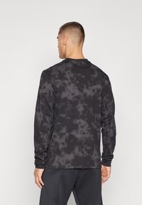 Long-sleeve shirt in black and grey tie-dye pattern, with soft fabric, crew neckline, and fitted sleeves. Designed for casual wear.