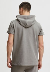 Sudadera corta de manga corta en color gris que cuenta con una tela texturizada, un ajuste relajado y una capucha con cordón, con puños enrollados y un diseño de espalda sin costuras.