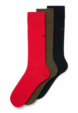Drei Paar Baumwollsocken in Rot, Olivgrün und Schwarz. Jedes Paar verfügt über einen gerippten Bund und ein kleines Logodetail an der Seite.