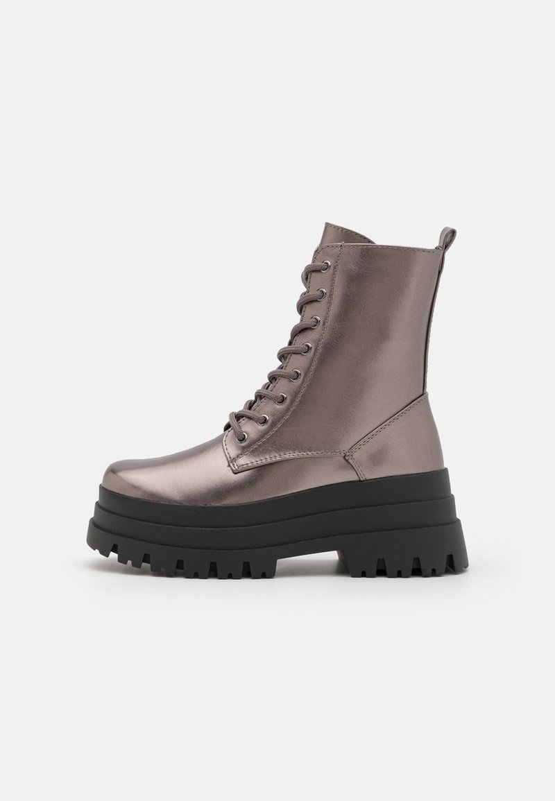 Botines metálico gris con una suela de goma negra gruesa, parte frontal con cordones y un tirador trasero reforzado para facilitar el calzado. Presenta una textura suave.