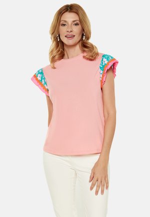 Top corto a maniche corte rosa con accenti blu, rosa e motivi floreali sui volant delle spalle. Tessuto morbido e strutturato e vestibilità rilassata.