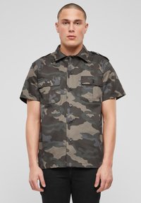 Korte mouwen camouflage shirt in tinten groen en grijs, met twee borstzakken, knoopsluiting en een platte kraag.