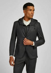 Grijze blazer met een afneembare capuchon, textuurstof, ritssluiting aan de voorkant en dubbele voorzakken, gecombineerd met een wit shirt eronder.