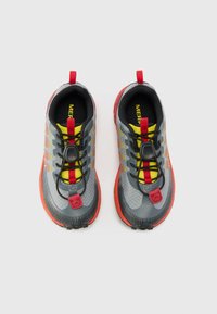 Grijze outdoorschoenen met zwarte en rode accenten, voorzien van een gestructureerde zool en een toggle vetersysteem. Felgele details verbeteren de zichtbaarheid.