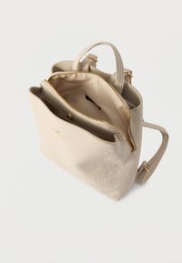 Μπεζ τσάντα χειρός με χρυστό φερμουάρ, ρυθμιζόμενους ιμάντες, κεντήματα με λουλούδια στο μπροστινό μέρος και πολλά εσωτερικά διαμερίσματα ορατά.