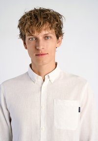 Witte linnen blouse met kraag, voorzien van een enkele borstzak. Subtiele textuur en geen gedrukt patroon.
