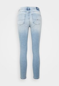 Jeans skinny de denim azul claro con un efecto desgastado, que presentan una etiqueta en la cinturilla, dos bolsillos traseros y una textura suave.