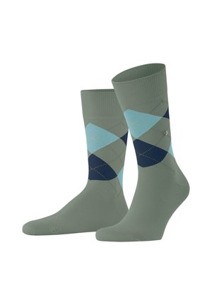 Un paio di calzini verde oliva a metà polpaccio con un motivo a rombi argyle blu e blu navy sui lati, su uno sfondo bianco.