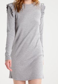 Abito grigio a coste con maniche lunghe, presenta dettagli a volant sulle spalle, una texture morbida e una silhouette aderente.