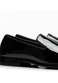 Czarne lakierowane mokasyny o eleganckim designie, z zaokrąglonym noskiem i płaską podeszwą. Gładka faktura z minimalistycznymi detalami.