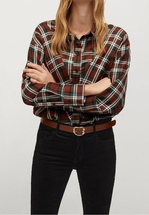 Brun og grøn ternet skjorte med krave og manchetter med knapper, kombineret med sort jeans med høj talje og et brunt bælte med guldlås.