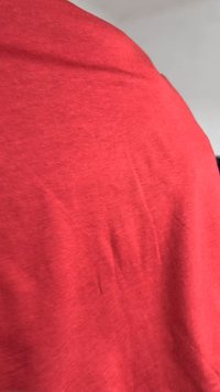 Tricou roșu, cu mânecă scurtă, realizat dintr-un material moale și texturat, având o ușoară elasticitate, cu o culoare uniformă și netedă.