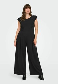Svart jumpsuit med volangdetaljer på korta ärmar, plisserade vida ben och en figursydd bodice. Tillverkad av ett slätt tyg och har en hög halsringning.