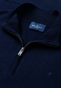 Granatowy sweter rozpinany na suwak, wykonany z miękkiego materiału, z srebrnym zamkiem błyskawicznym i haftowanym logo na piersi.