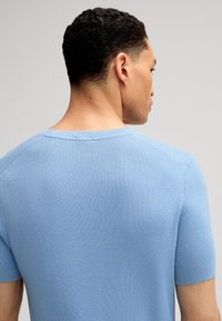 Maglione a maniche corte di colore blu chiaro, in maglia, con un motivo testurizzato e scollatura a girocollo, che presenta una vestibilità rilassata e dettagli di cucitura sulle spalle.