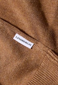 Tessuto lavorato a maglia marrone con un motivo fine e tessurato. Un'etichetta bianca con "LINDENBERGH" è cucita nella cucitura laterale.