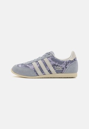 Lavprofil Adidas Japan-sneaker med gråt ruskind, lilla slange-mønsterstof, cremefarvede striber og beige sål på hvid baggrund.