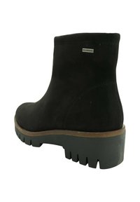 Bota de tobillo negra impermeable con suela gruesa de tacos y borde marrón a lo largo del borde de la suela, vista desde atrás y desde el lado.