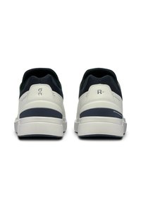 Scarpe sportive bianche e blu navy con parte superiore in rete, colletto imbottito, suola testurizzata e una striscia blu a contrasto lungo il retro.