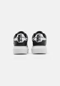 Schwarze und silberne Sneakers mit einem glatten Lederoberteil, weißer Sohle und metallischen Akzenten an der Ferse mit Markenlogo.