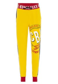 Gelbe Sweatpants mit einem elastischen Bund in Rot und Schwarz, seitlichen Streifen und kräftigem grafischem Text in Rot und Weiß auf der Vorderseite.