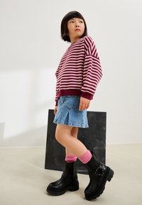 Maglione a righe bordeaux e rosa, minigonna di jeans, stivaletti neri, calzini rosa. Design semplice con vestibilità rilassata e materiali lavorati.
