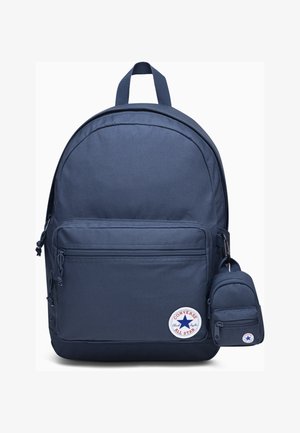 Navyfarbener Stoffrucksack mit runder Form, vorderer Reißverschlusstasche, seitlichen Zugbändern und einer kleinen abnehmbaren Tasche. Mit einem runden Logo.