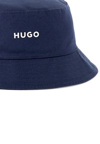 Chapeau seau bleu marine en tissu de coton. Avec un bord courbé et logo "HUGO" brodé en blanc à l'avant.