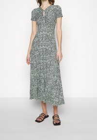 Maxi dress in green and black with a zebra print design. Features short sleeves and a keyhole neckline, made of a soft, textured fabric.