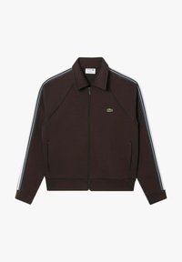 Chaqueta marrón con cremallera y cuello, con rayas azules y blancas en los hombros y un logo verde en el pecho izquierdo. Tejido liso y diseño ajustado.