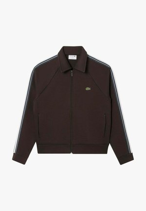 Brun lynlåsjakke med krave, med blå og hvide skulderstriber og et grønt logo på venstre bryst. Glat stof og tætsiddende design.