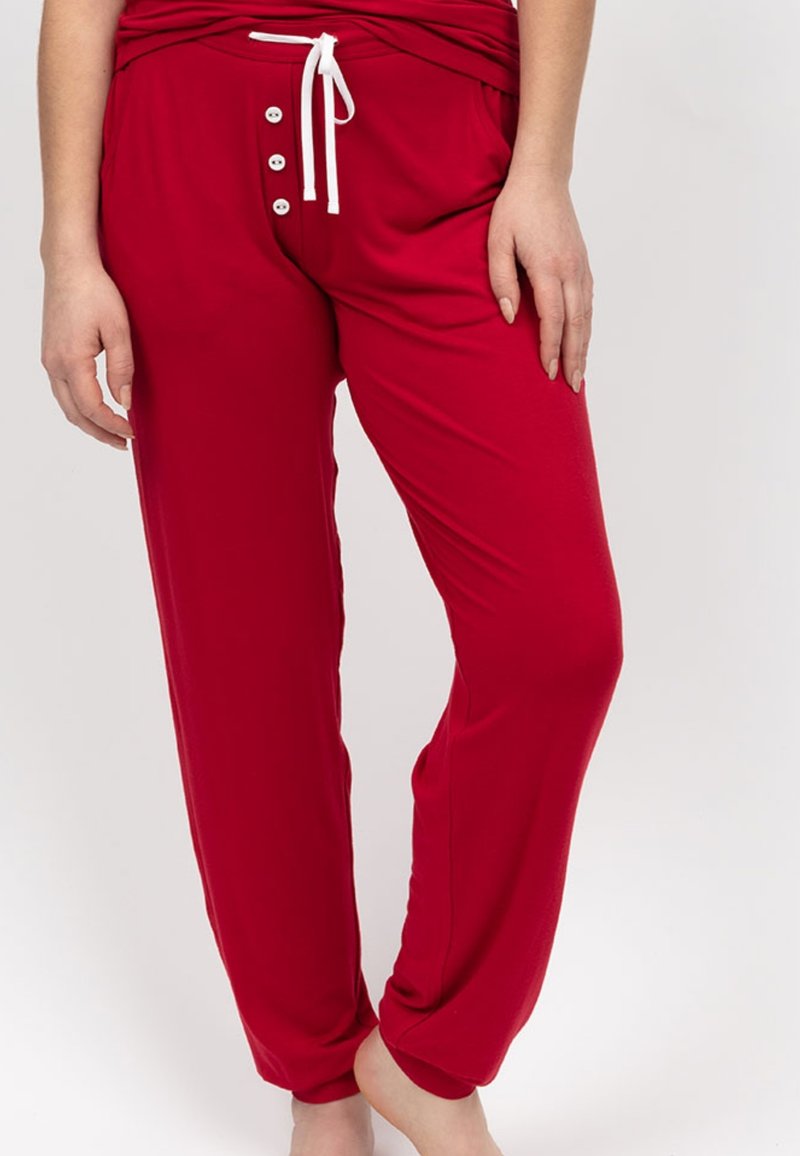 Rode loungebroek van zacht materiaal, met een verstelbare tailleband, witte knoopaccenten en zijzakken voor extra functionaliteit.