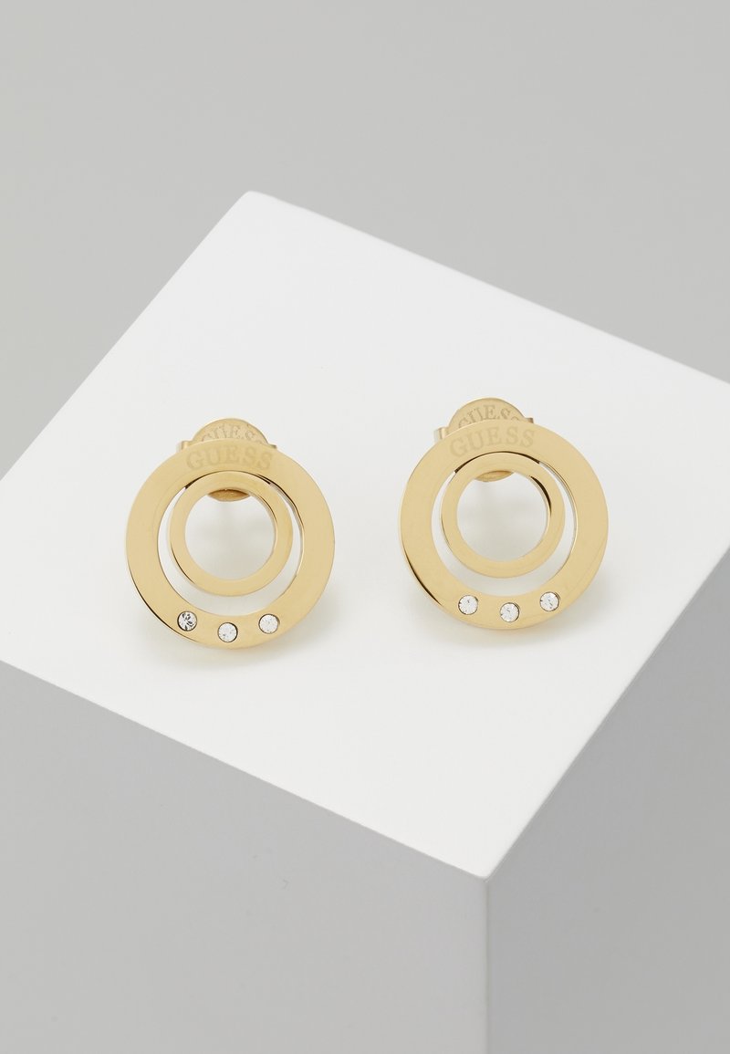 Boucles d'oreilles clous circulaires en or avec deux anneaux concentriques, trois petits cristaux sur l'anneau extérieur et la marque gravée sur le dessus.