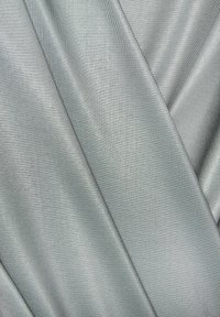 Tejido gris claro con una textura suave y sedosa y un brillo sutil. Presenta pliegues diagonales que muestran un delicado patrón tejido.