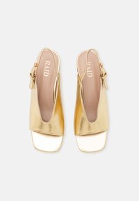 Kultaiset metalliset slingback-sandaalit, joissa on neliön muotoinen kärki, sileä pinta ja säädettävä hihna. Brändinimi "RAID" on näkyvillä pohjallisessa.