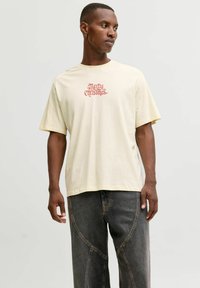 Cremefarvet kortærmet t-shirt med "Merry Christmas" i rød design på fronten. Blødt stof, løs pasform og standard rund halsudskæring.