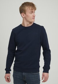 Sweatshirt bleumarin, cu guler rotund, mâneci lungi, fabricat dintr-un amestec de bumbac. Prezintă manșete și tiv ribbed, detaliu subtil cu logo pe piept.
