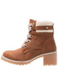 Bottine cheville en daim brun avec une doublure en polaire blanche texturée, un design à lacets, des oeillets dorés et un talon épais. Semelle en caoutchouc renforcé.