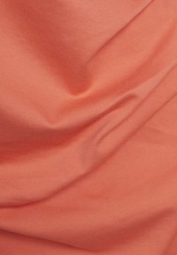 Tissu lisse de couleur corail avec des plis doux et une texture tissée subtile remplissant tout le cadre.