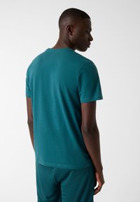 Teal short-sleeve t-shirt with a crew neck, featuring a smooth texture and a relaxed fit, shown from the back.