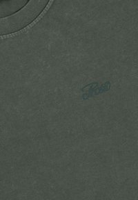 Ciemnozielona koszulka z krótkim rękawem o miękkiej teksturze i okrągłym dekolcie. Posiada subtelne logo w ciemniejszym odcieniu zieleni na piersi.