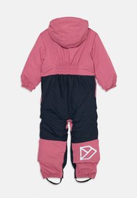 Rosa og navy vanntett snødrakt med hette, elastisk midje og fotstropper. Har en hvit geometrisk logo på benet.