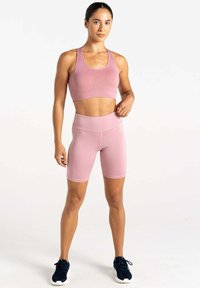 Sujetador deportivo de color rosa claro y pantalones cortos de ciclismo de cintura alta a juego, hechos de una tela elástica con una textura suave y costuras mínimas.